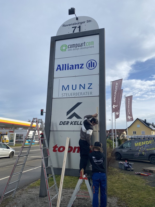 Ein Mann benutzt eine Leiter, um ein Schild anzubringen.